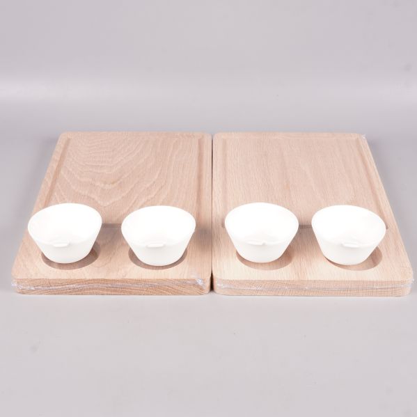 Två träplankor med fyra vita skålar uppställda