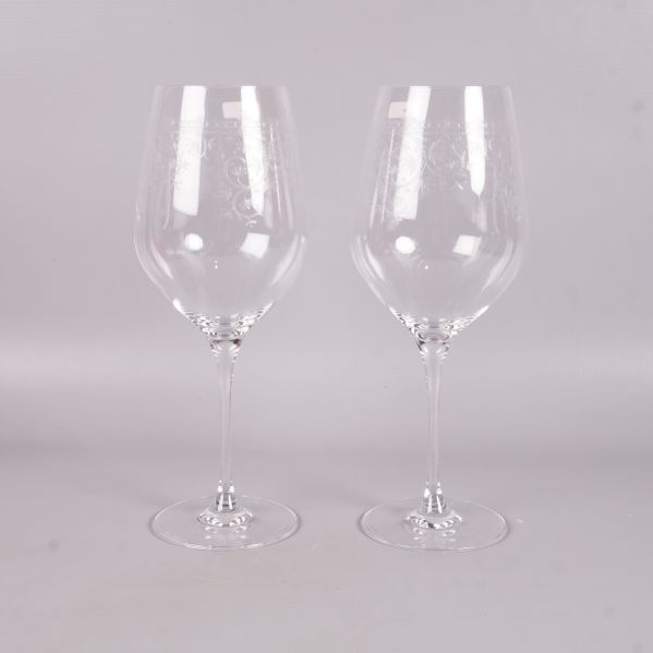 Framifrån två vinglas med tunn stjälk och graverat motiv