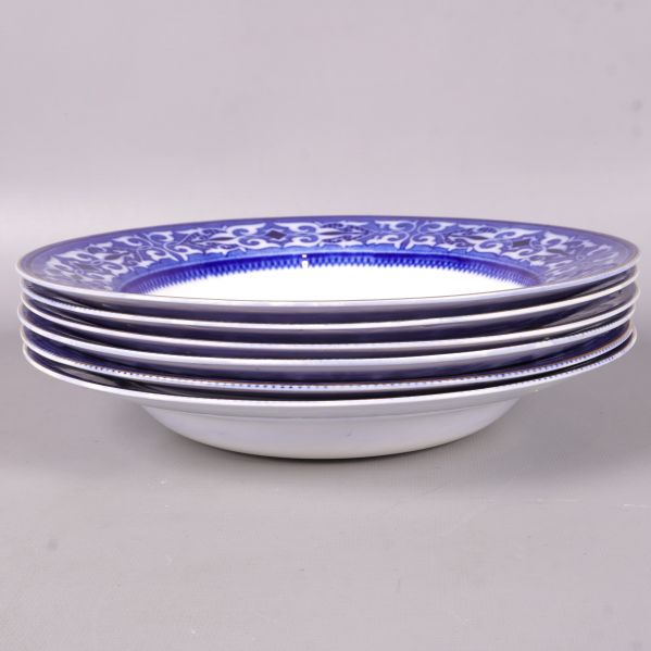 Sex djupa tallrikar med blå kant staplade på varandra