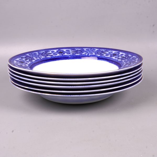 Sida av staplade djupa tallrikar med blåvit dekor