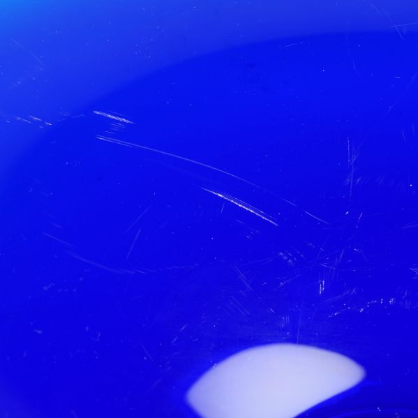 Närbild på repor i blått glas på fatets yta