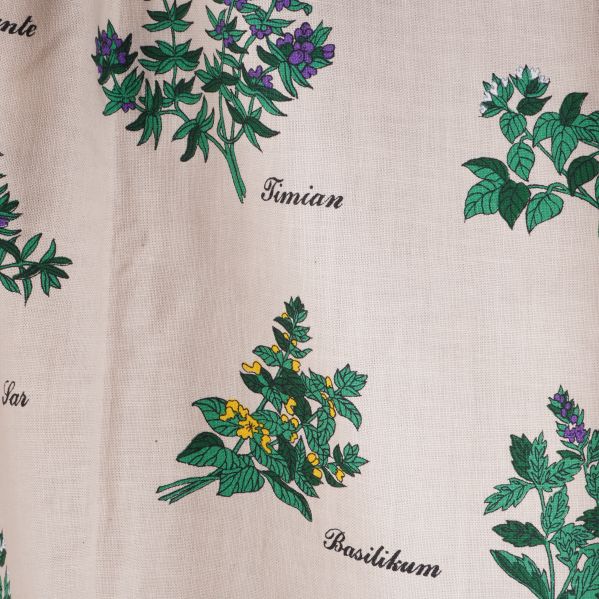 Närbild på örtmotiv och växtnamn på gardintyget