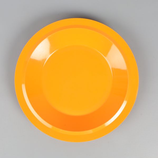 En orange djup tallrik ovanifrån mot grå bakgrund