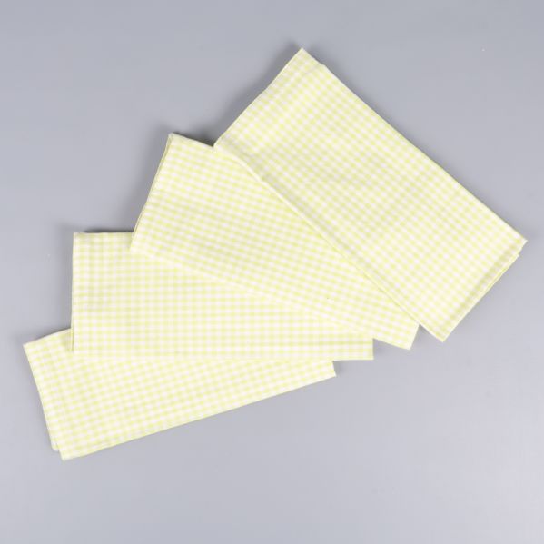 Fyra ljusgröna och vita rutiga servetter utlagda på grå bakgrund