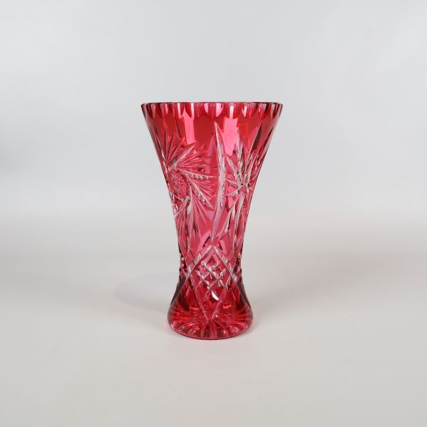 Röd handslipad kristallvas i helfigur mot vit bakgrund