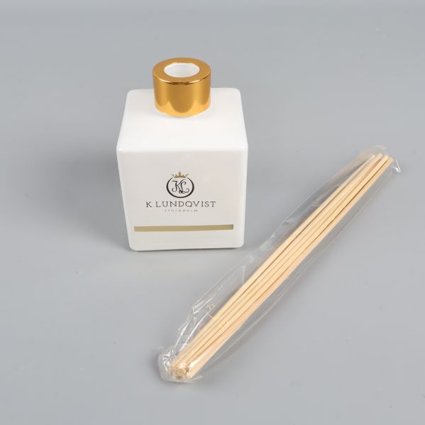 Närbild på fyrkantig flaska och doftpinnar