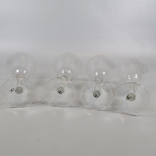 Fyra vinglas liggande på sidan på vitt underlag