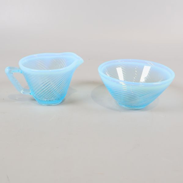 Blå gräddkanna och sockerskål i glas från sidan