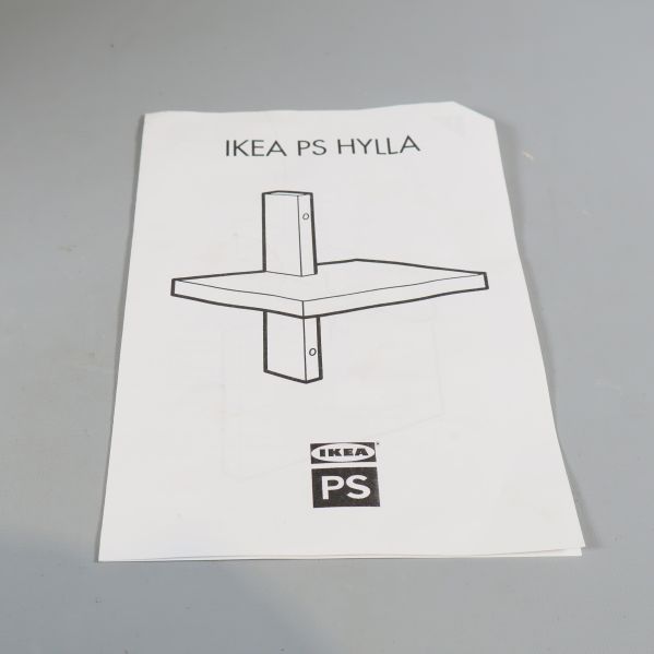 Bruksanvisning IKEA PS HYLLA ligger på ett bord