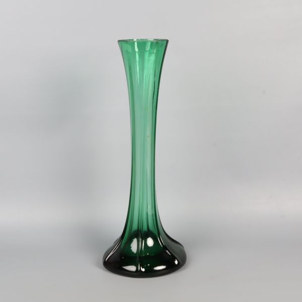 Hög grön glasvas med bred fot mot vit bakgrund