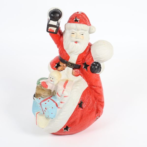 Tomte i röd dräkt med lykta och säck fylld med paket