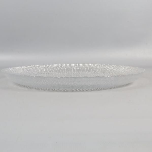 En stor transparent tallrik av glas från sidan