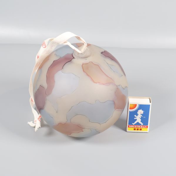 Glaskula i pastelltoner bredvid tändsticksask