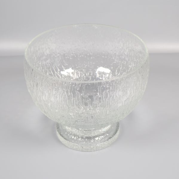 Strukturerad glasskål på fot mot ljus bakgrund