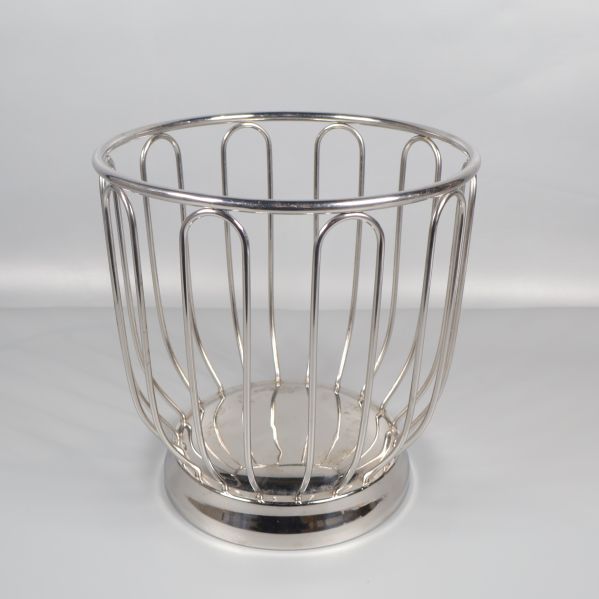 Rund trådkorg i metall sedd framifrån på vit bakgrund