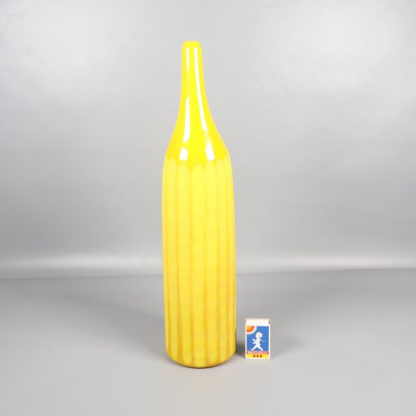 Hög gul vas jämte tändsticksask