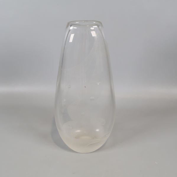 Stor transparent vas med rundad form mot grå bakgrund