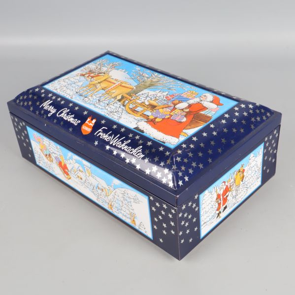 Blå metallburk med vita stjärnor och julmotiv på sidor och lock