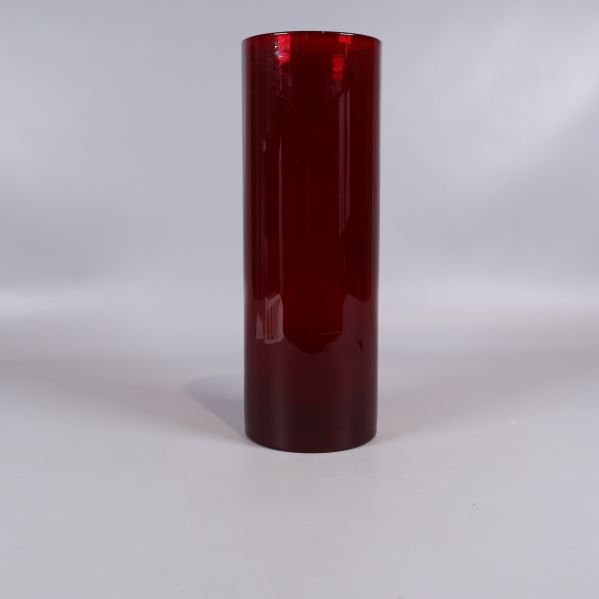 Röd cylinderformad vas sedd rakt framifrån mot vit bakgrund