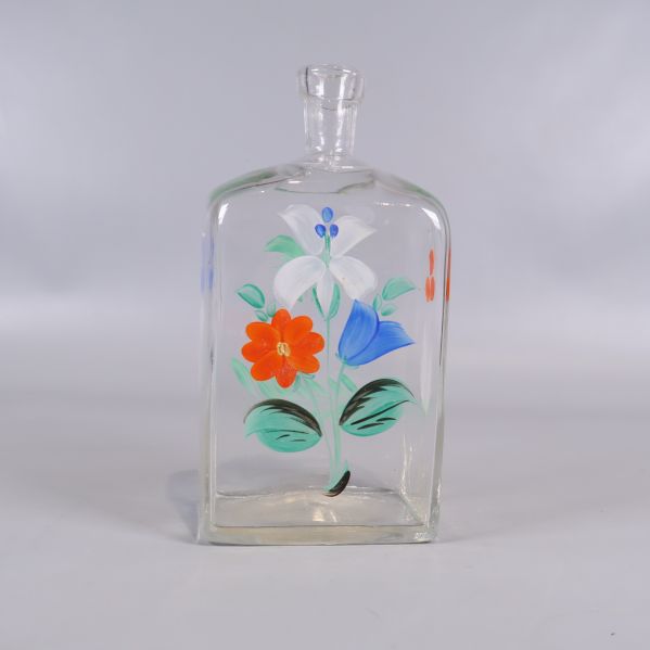 Framsida av glasflaska med färgglada blommor och blad