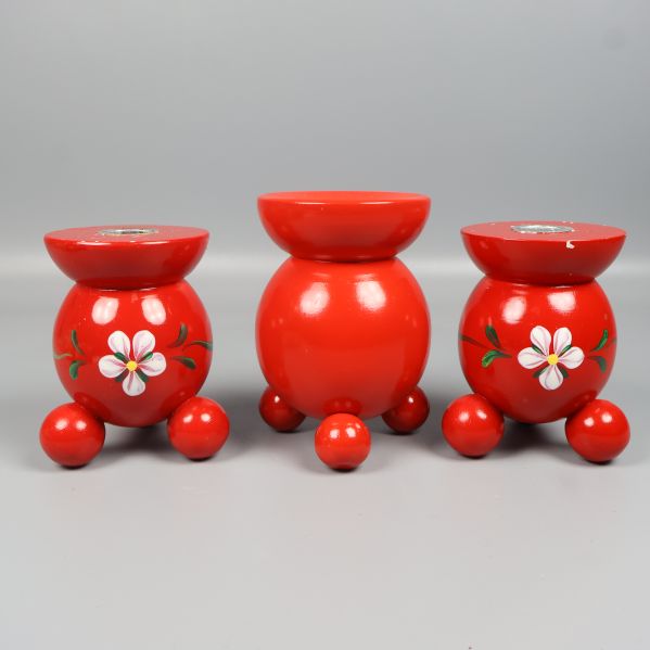 Tre röda ljusstakar med målade blommor framifrån