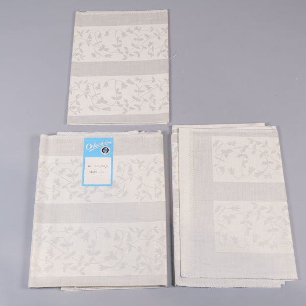 Tre vikta vita linservetter med blommotiv