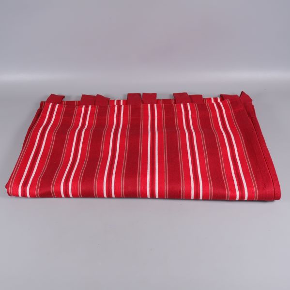 Röd gardin med vita ränder ligger vikt