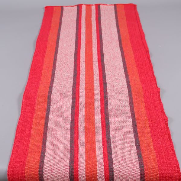 Lång randig löpare utrullad med röda och rosa toner