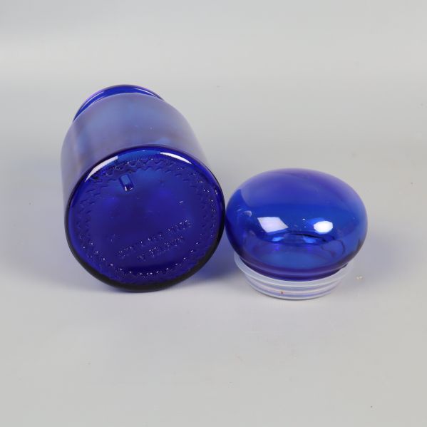 Blå apoteksburk med avtaget lock liggande bredvid