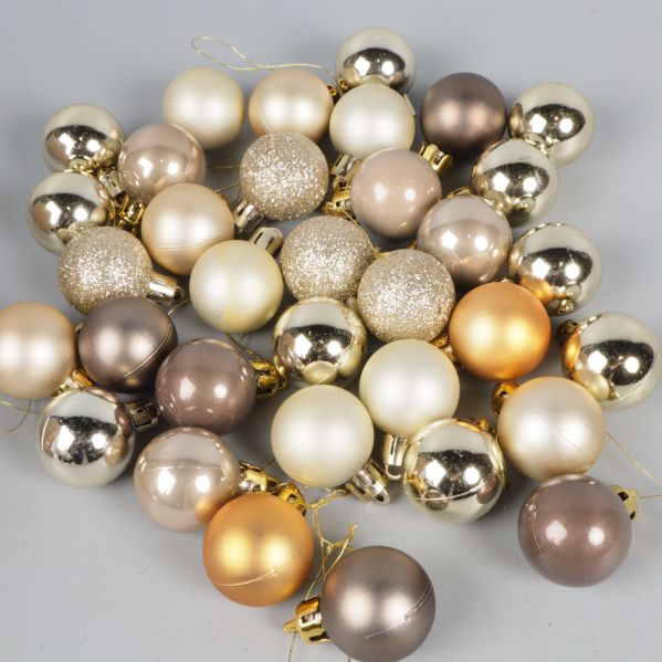 Guld- och silverfärgade julkulor liggande på grått underlag