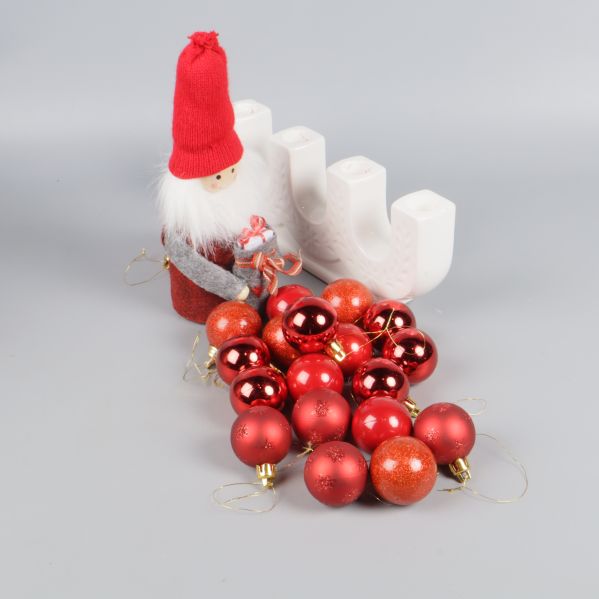 Röda julkulor framför tomte och adventsljusstake