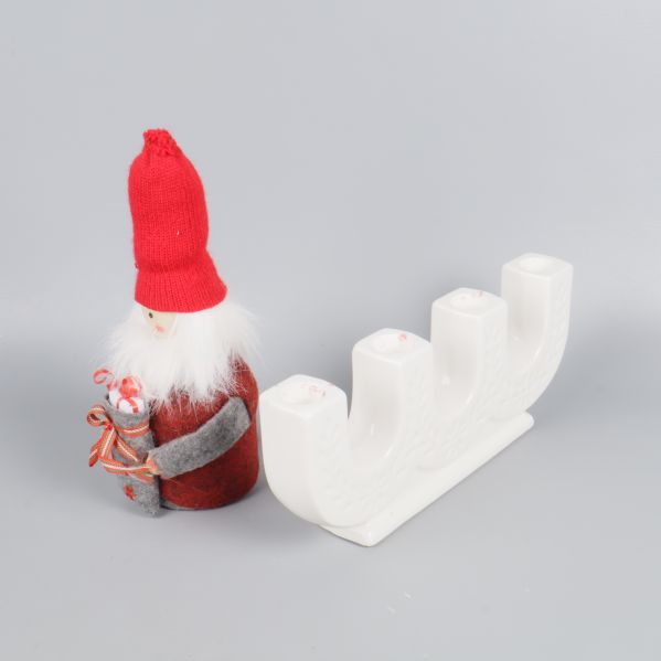 Tomtefigur intill vit adventsljusstake från sidan