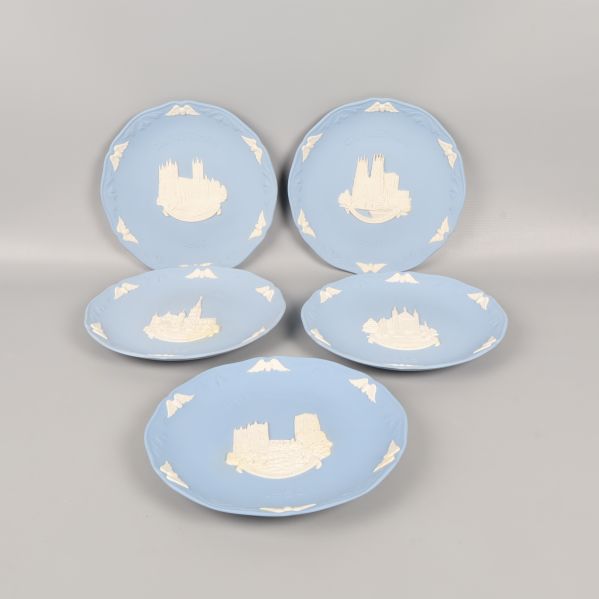 Fem blå tallrikar med vita reliefer och motiv