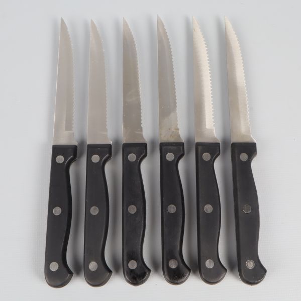 Sex köttknivar med svarta handtag och tandade blad