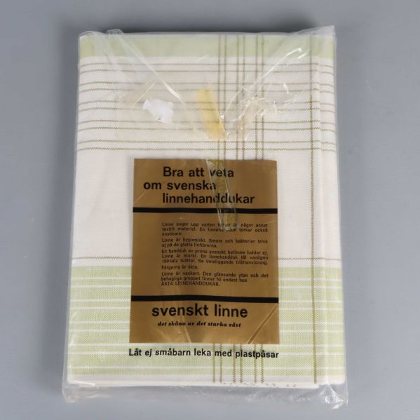 Handduk i halvlinne med grönvitt rutmönster och informativ etikett om svenskt linne