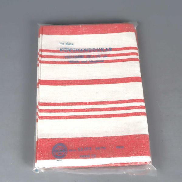 Rödvit randig kökshandduk i förpackning mot grå bakgrund