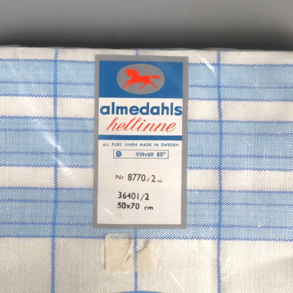 Närbild på Almedahls etikett och handdukens rutiga mönster