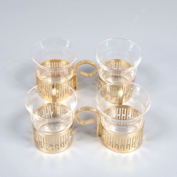 Fyra glaskoppar med guldfärgade hållare arrangerade i fyrkant
