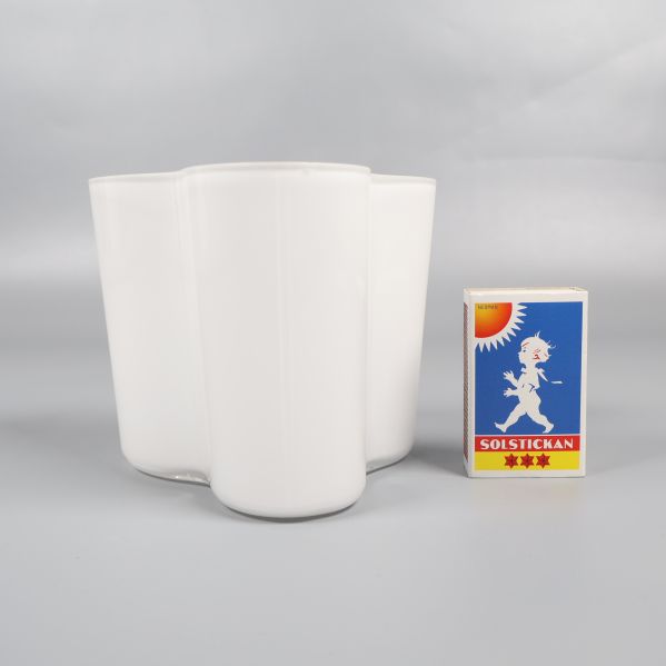 Vit vas bredvid tändsticksask för storleksjämförelse