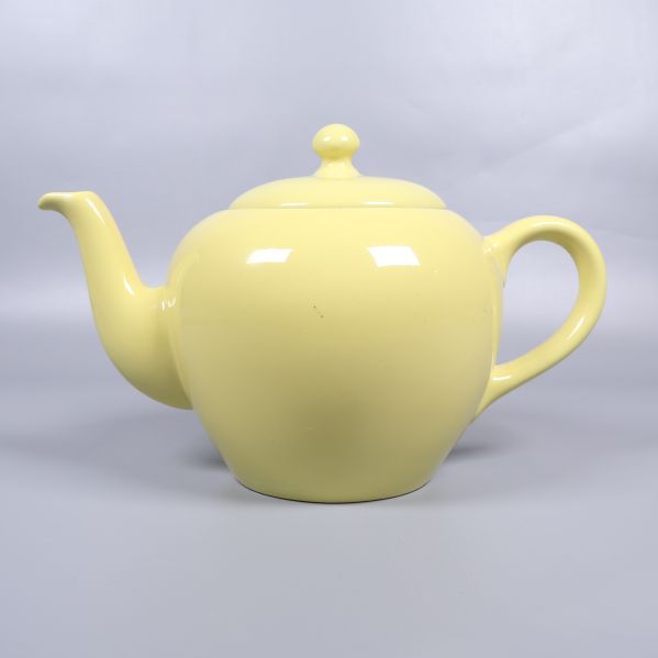 Tekanna i gult porslin sedd från sidan