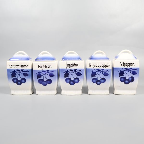 Fem blåvita kryddburkar med olika örtetiketter