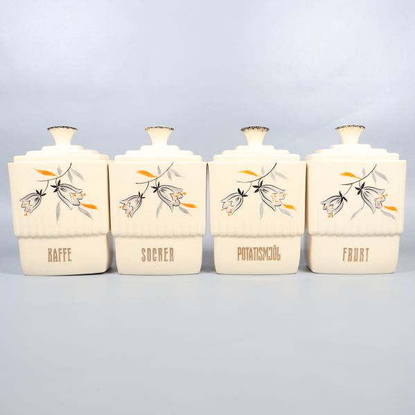 Fyra stora förvaringsburkar med handmålade blommor uppradade