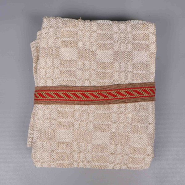 Närbild på vikt beige linnéhandduk med röd bård