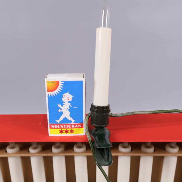 Vit elektrisk julgranslampa jämte tändsticksask för storleksjämförelse