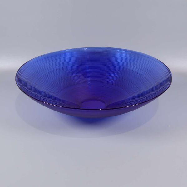 Stor blå skål i glas med rund form sedd snett framifrån