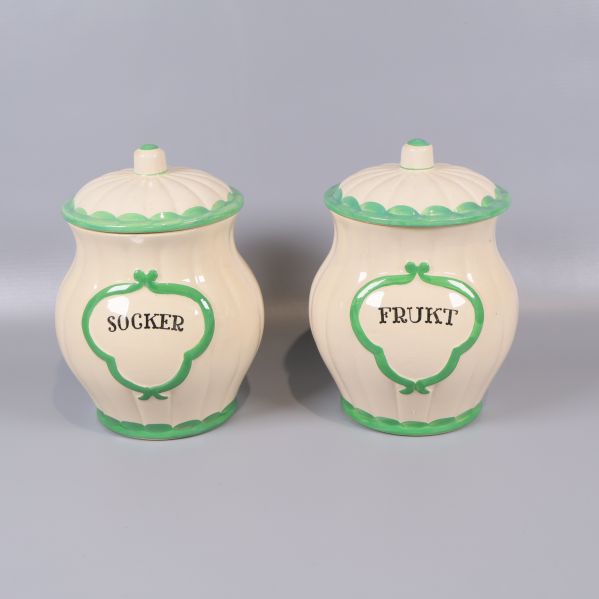 Två gräddvita burkar med grön kant och texten socker frukt