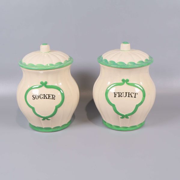 Två burkar med lock och grön dekor, text socker och frukt
