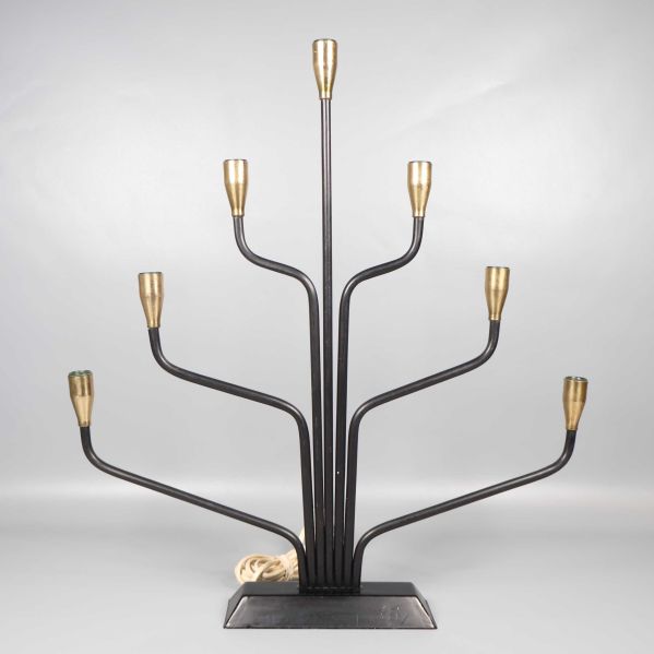 Sjuarmad svart ljusstake med mässingsdetaljer mot grå bakgrund