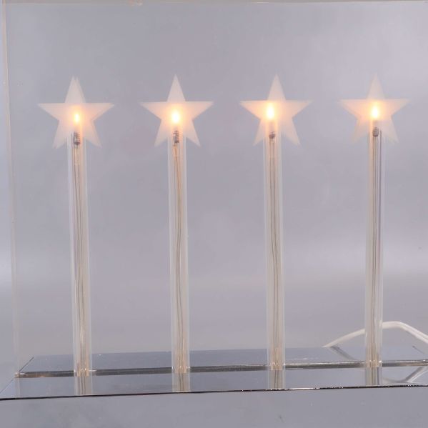 Närbild på fyra lysande stjärnor i adventsljusstake