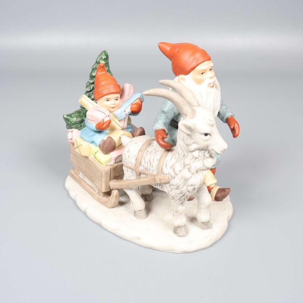 Tomtefigur med bock och släde på vit yta